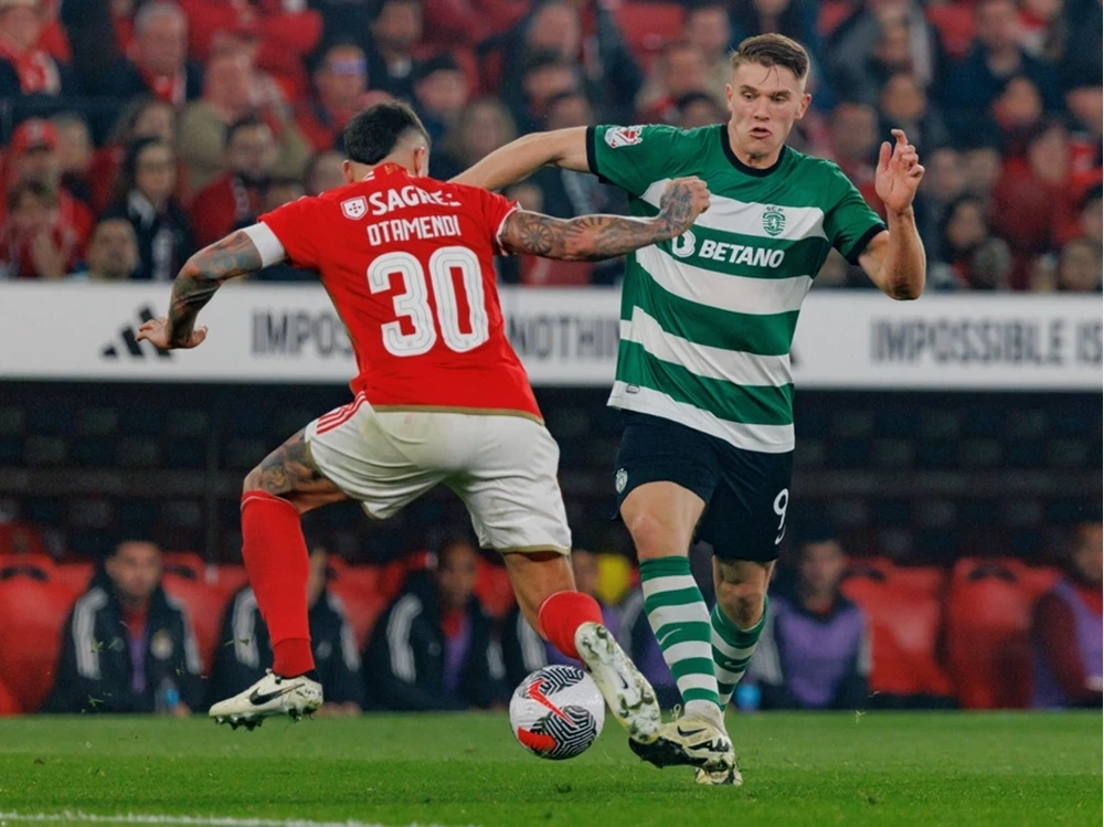 Fußballreise Primeira Liga – Das hitzige Derby in Lissabon live erleben Ein intensiver Zweikampf um den Ball zwischen zwei Spielern im rot-weißen und grün-weiß gestreiften Trikot während eines Primeira Liga Spiels.